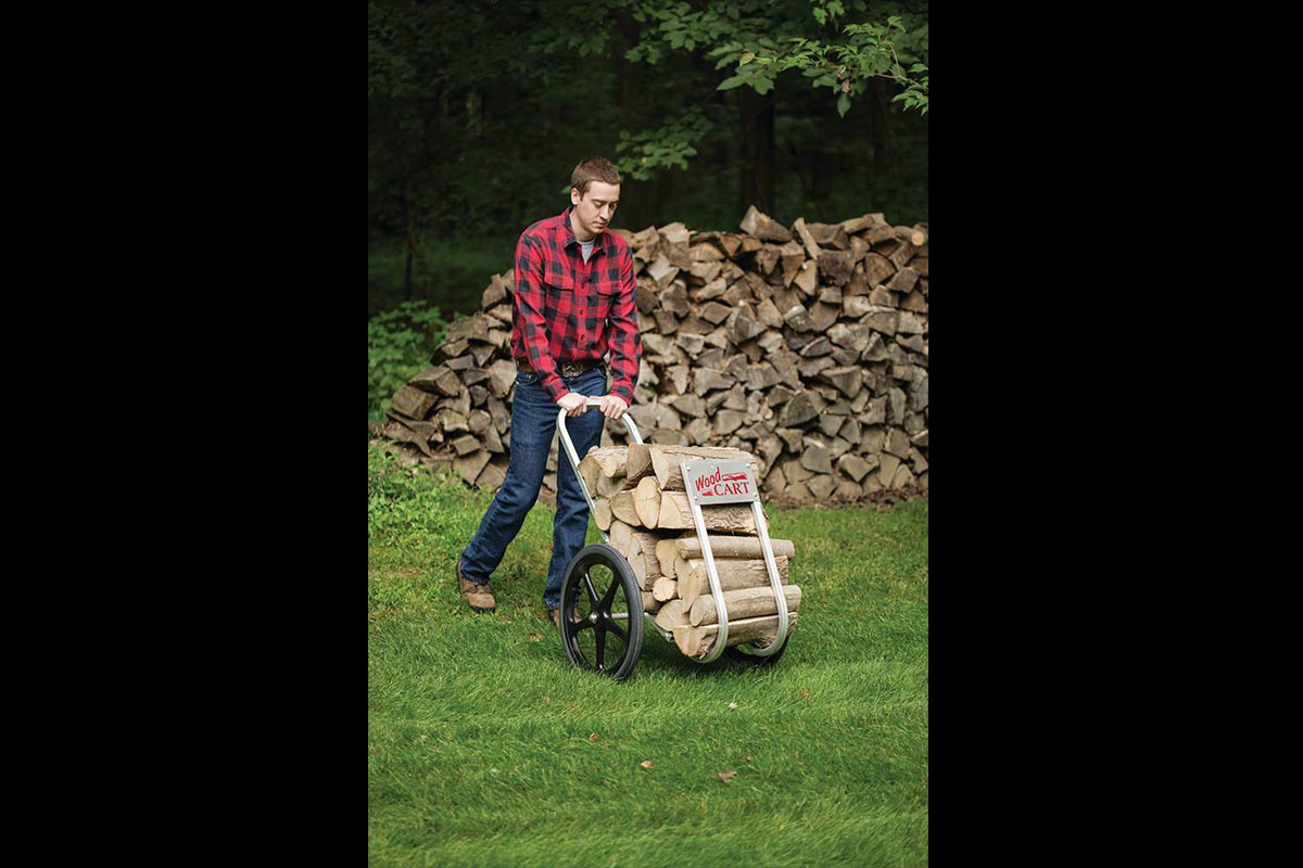 Man pushing an Amish-made cart full of chopped wood.