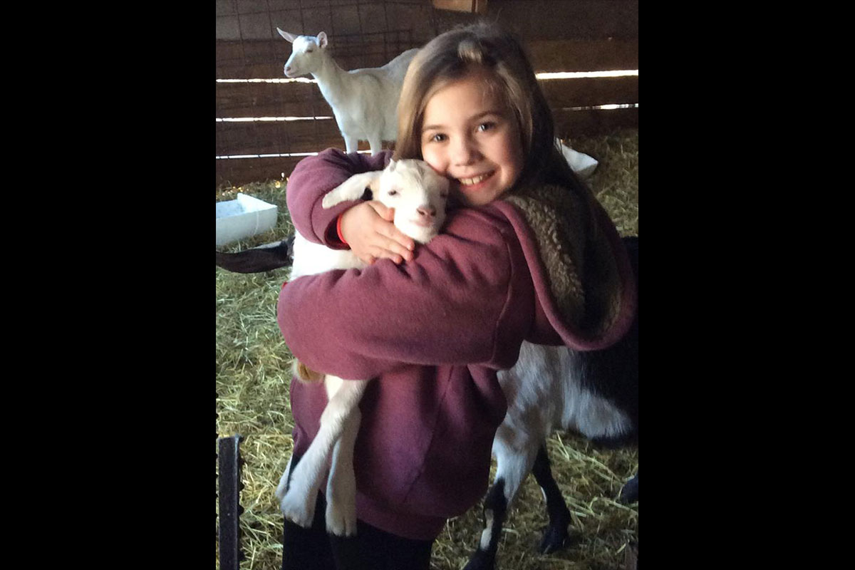 Young girl hugging a kid (baby goat)