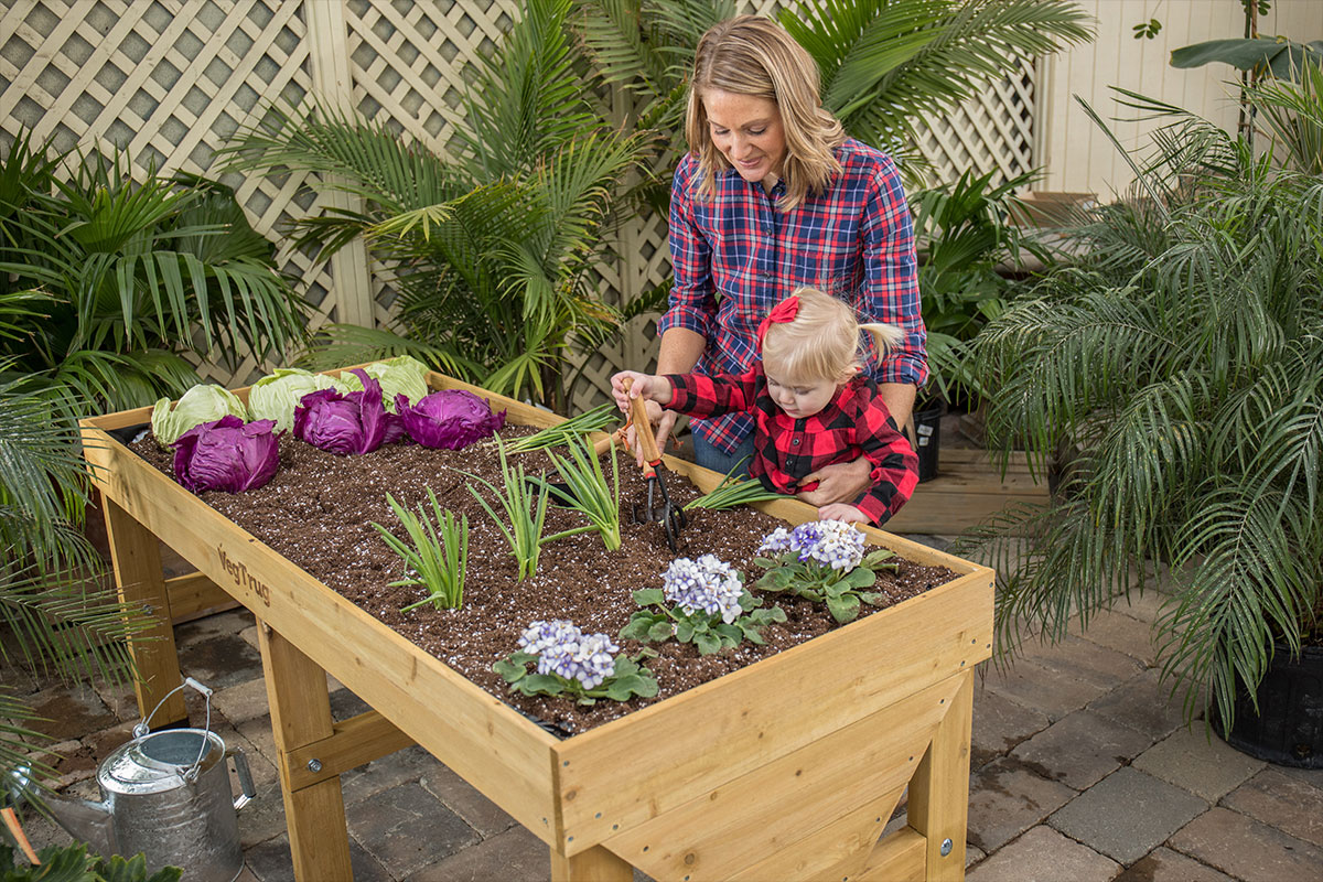 Woman gardening in a VegTrug elevated garden bed with her young daughter