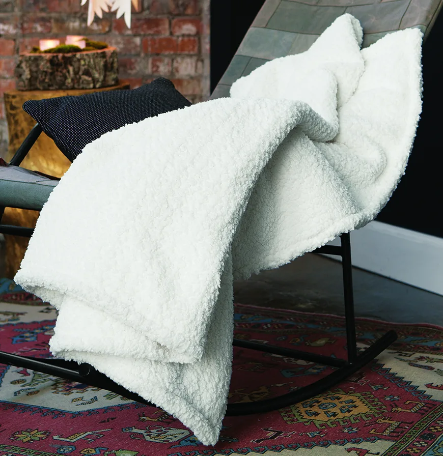 Snowy Luxe Winter Throw draped over a rocking chair