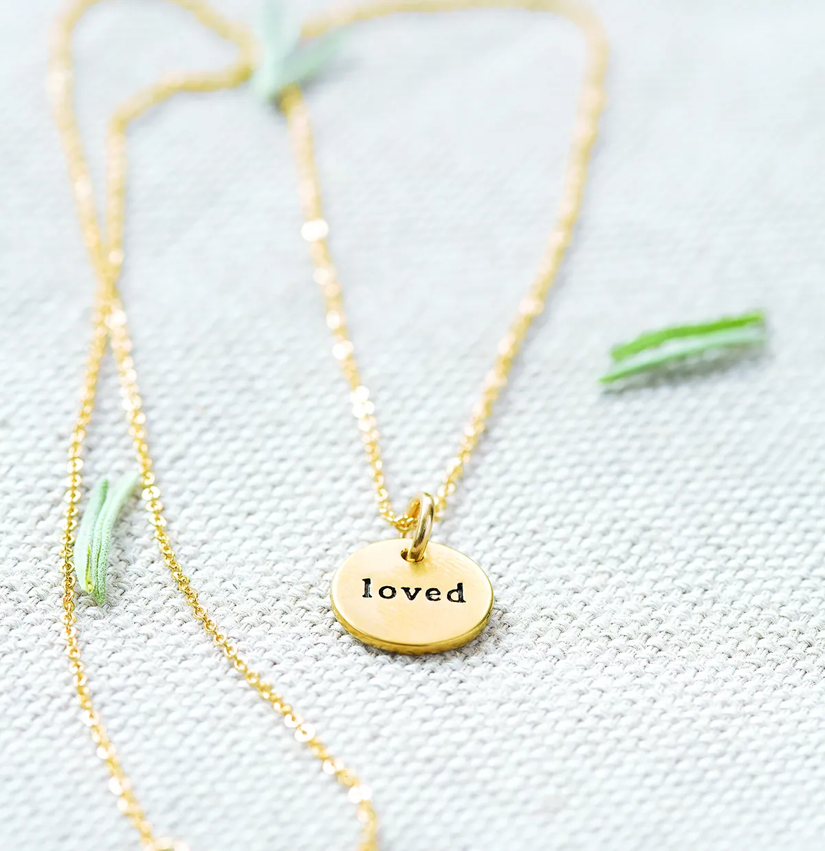 Loved Circle Necklace: a small gold charm stamped with the word loved on a fine gold chain