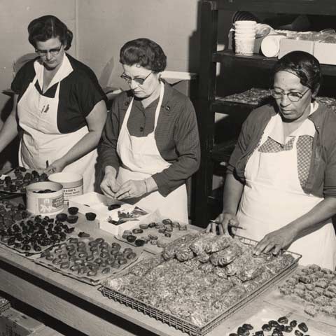 Creating gift boxes with various pecan treats, including flavored pecans, pecan brittle, and pecan logs.