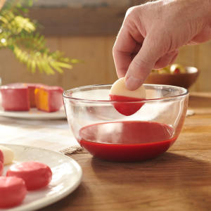 cheese being dipped into red cheese wax